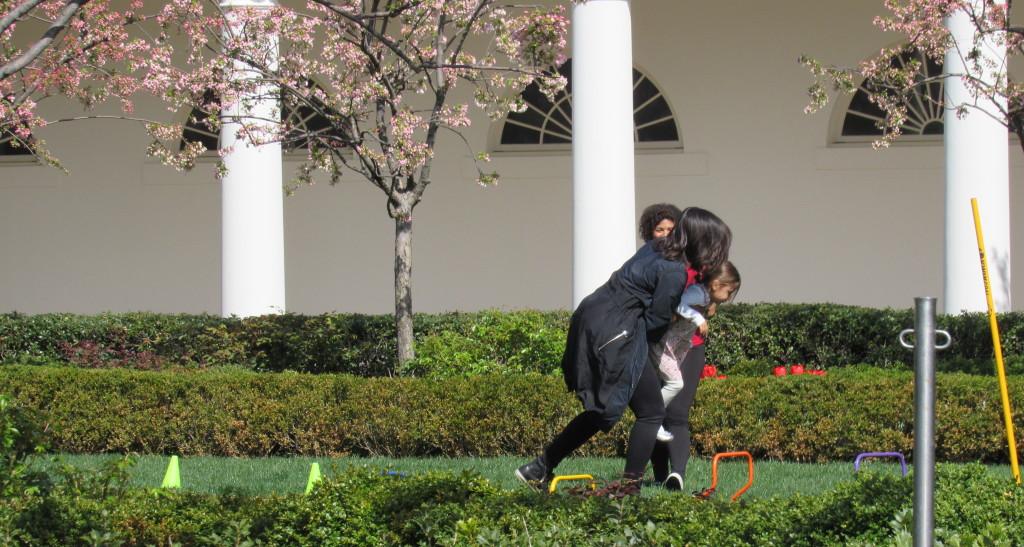 Michelle Obama helping to carry a little boy to the end of the obstacle course photo: Sara Monterroso)