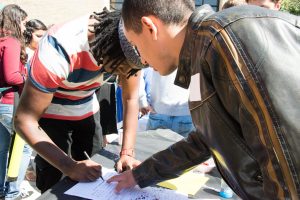 Karim, member of The Filmmaking club, helps a future member signing in. (Photo. Adriano Cassoma)