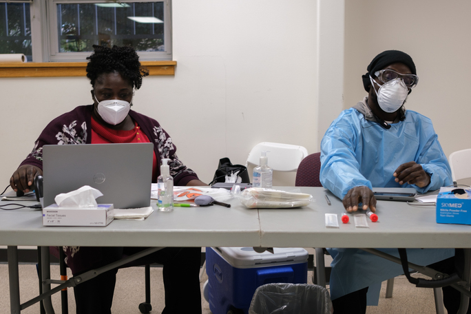 Anne Boa is responsible for collecting patient information and Demetrius Eady is responsible for performing COVID testing at Montgomery College Rockville Campus. Photo by Michael Hyman.