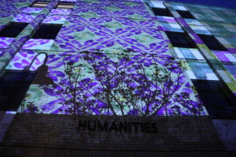 Montgomery College Rockville’s Humanities and Campus Center buildings illuminated with projections of 2-D Design students community quilt of patterns on April 13, 2023. (Photo Credits: Alana McCarthy Light)