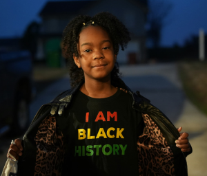 Picture of a girl wearing a shirt that reads, "I Am Black History" Photo Credit: Anthony McKissic on Unsplash 